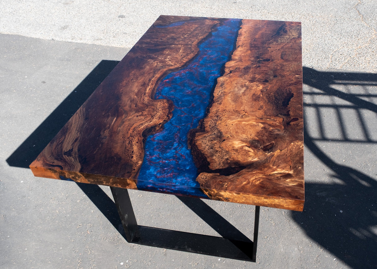 Wooden table with a blue and red resin river on a concrete surface