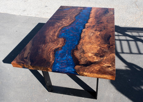 Wooden table with a blue and red resin river on a concrete surface