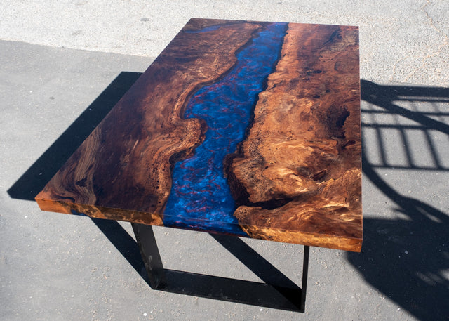 Wooden table with a blue and red resin river on a concrete surface